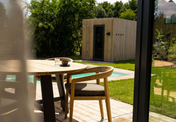 Terrazza esterna con tavolo e sedie in legno, vista su piscina e sauna a Unbrick One a Brinckerduyn, Paesi Bassi.