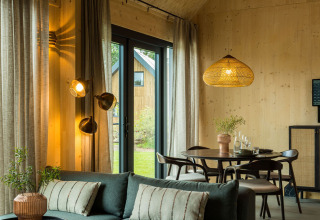 Modern lodge-interieur met houten panelen, zithoek en grote ramen in Brinckerduyn, Nederland.