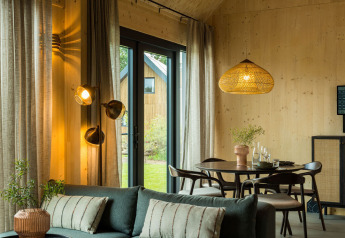 Interior de casa moderna con paneles de madera, comedor, sofá y grandes ventanas en Brinckerduyn, Países Bajos.