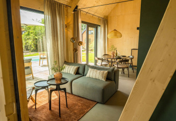 Sala de estar moderna de lodge con grandes ventanales, vista a la terraza y comedor en Brinckerduyn, Países Bajos.