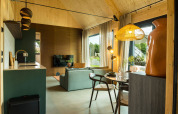 Modern lodge with open kitchen, dining area, and cozy living room at Unbrick One | Sauna and Pool in Brinckerduyn, Netherlands.