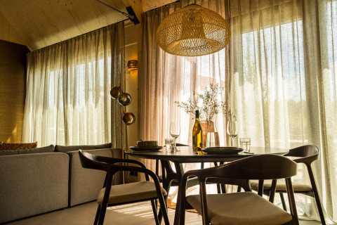 Sala da pranzo moderna con sedie in legno e luce soffusa presso Unbrick One Lodge nei Paesi Bassi.