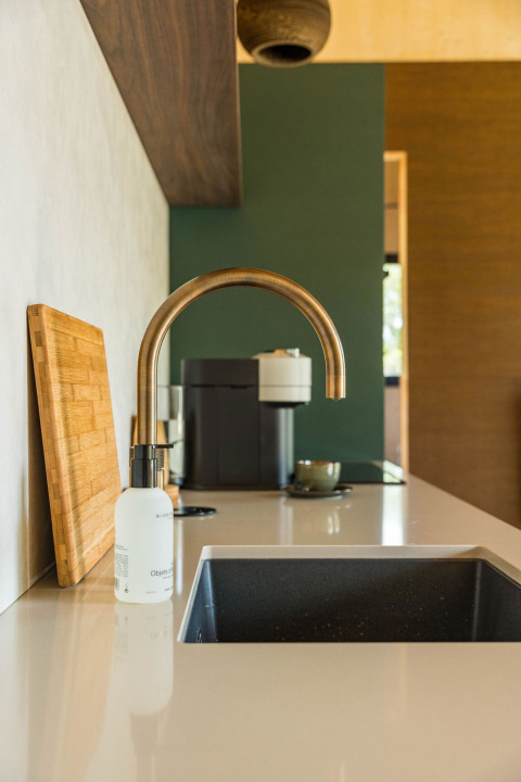Fregadero moderno con grifo dorado, tabla de cortar y cafetera en Unbrick One | Sauna and Pool en Brinckerduyn.