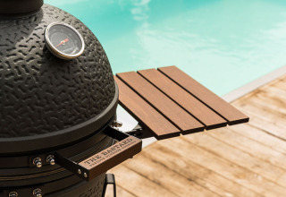 Barbecue in ceramica nera con ripiano in legno vicino alla piscina a Unbrick One | Sauna e Piscina a Brinckerduyn, Paesi Bassi.