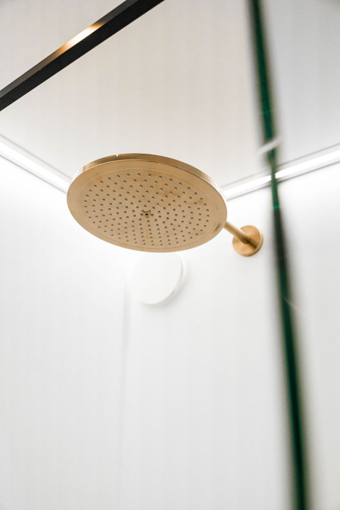 Goldfarbener Duschkopf in moderner Dusche bei Unbrick One | Sauna und Pool im Brinckerduyn, Niederlande.