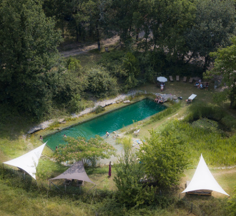 Luchtzicht op een natuurlijke zwemvijver bij Eco domaine Le Camp, een vakantiedomein in Occitanië, Frankrijk.