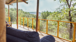 Gemütliche Veranda im Lodgetent Samburu mit Blick auf grüne Berge und bewaldete Landschaft in der Sonne.