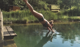 Mujer bucea en una piscina natural en Eco domaine Le Camp, un parque vacacional en Occitania, Francia.