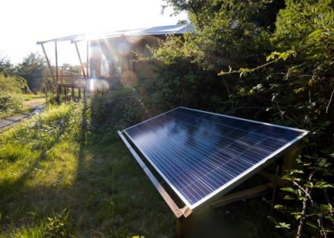 Solarmodul im Grünen vor einer Hütte im Eco domaine Le Camp, einem Ferienpark in Okzitanien, Frankreich.