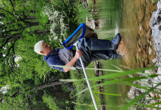 Person i waders fisker ved søbred omgivet af frodig vegetation i Eco domaine Le Camp, Occitanie, Frankrig.