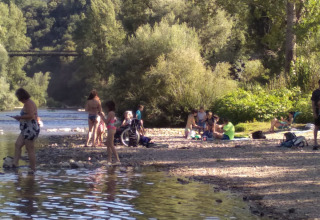 Folk nyder en sommerdag ved en flod i Eco domaine Le Camp, beliggende i det naturskønne Occitanie, Frankrig.