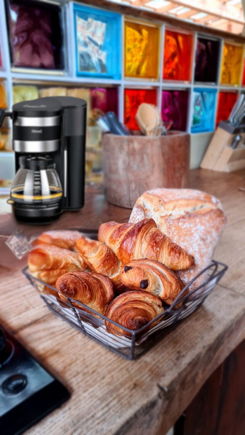 Ontbijttafel bij Eco Domaine Le Camp met koffie, croissants en brood op een rustieke houten toog in Occitanië.