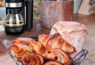 Et morgenbord på Eco Domaine Le Camp med kaffe, croissanter og brød på en rustik træbordplade i Occitanie.