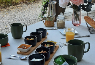 En udendørs morgenmad i nærheden af Varen, Occitanie, med kaffe, juice, brød og blomsterpynt.