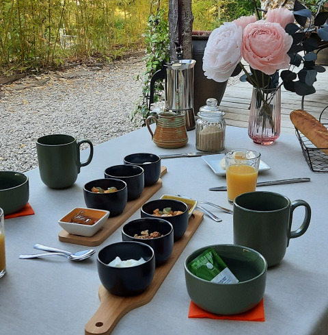 En udendørs morgenmad i nærheden af Varen, Occitanie, med kaffe, juice, brød og blomsterpynt.