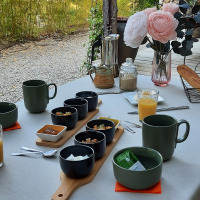 Mesa de desayuno al aire libre cerca de Varen, Occitania, con café, jugo, pan y flores en el campo.