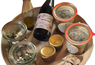 Serveringsbakke med vin, brød, salater i glas og små beholdere, set i Eco domaine Le Camp, Occitanie.