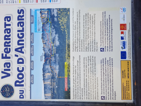 Panel informativo de la Via Ferrata du Roc d'Anglars en Occitania, Francia, con rutas y datos de seguridad.
