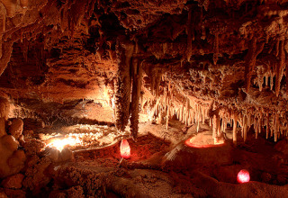 Stalaktitfyldt grotte oplyst af varme lamper nær Varen, Occitanie, Frankrig, med et mystisk og naturligt miljø.