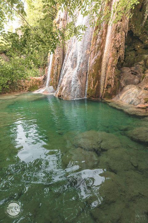 Wunderschöner Wasserfall bei Varen, Occitanie, Frankreich, umgeben von grüner Natur und klarem Wasser.