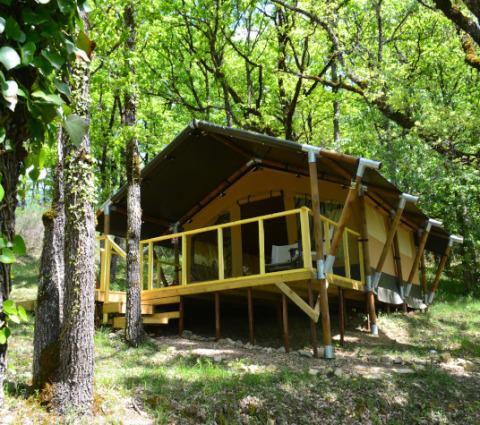 Tent Shimoni, a safari tent at Eco domaine Le Camp in France, surrounded by lush green forest.