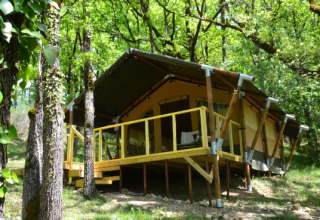 Tent Shimoni, a safari tent at Eco domaine Le Camp in France, surrounded by lush green forest.