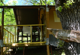 Safari-teltet Shimoni ved Eco domaine Le Camp i Frankrig, omgivet af træer og en rustik træterrasse.