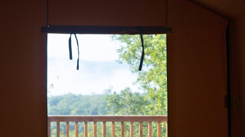 Blick aus dem Lodgetent Chrysalide im Eco domaine Le Camp in Frankreich auf einen Balkon mit Natur.