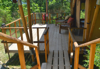 Terraza de madera junto a una tienda safari en Eco domaine Le Camp, Francia, rodeada de naturaleza.