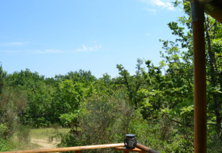 Vista desde la tienda safari Lodgetent Meru en Eco domaine Le Camp, Francia, con vegetación y cielo azul.