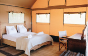 Interno della tenda safari Lodgetent Samburu all’Eco domaine Le Camp in Francia, con letto e scrivania.
