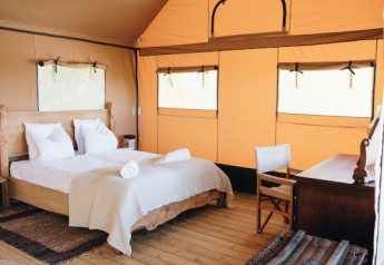 Indretning af et hyggeligt soveværelse inde i Lodgetent Samburu på Eco domaine Le Camp, Frankrig.