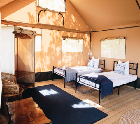 Indretning af Lodgetent Samburu på Eco domaine Le Camp i Frankrig med to enkeltsenge og naturligt lys.