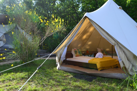 Safari-Zelt Lodgetent Samburu bei Eco domaine Le Camp in Frankreich mit gemachtem Bett und gelber Decke.