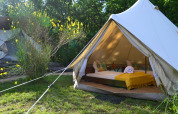 Safaritent Lodgetent Samburu bij Eco domaine Le Camp in Frankrijk, met bed en gele deken binnenin.