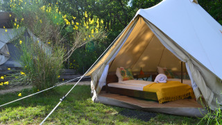 Tienda safari Lodgetent Samburu en Eco domaine Le Camp, Francia, con cama y manta amarilla en el interior.