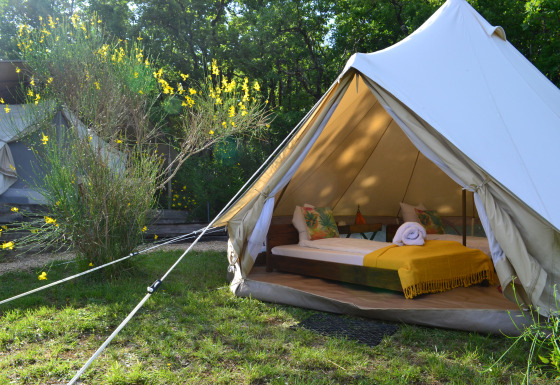 Safari-teltet Lodgetent Samburu på Eco domaine Le Camp i Frankrig med komfortabel seng og gul plaid.
