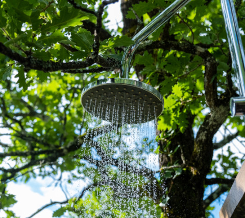 Cabeza de ducha exterior con agua fluyendo entre árboles en Lodgetent Samburu, Eco domaine Le Camp, Francia.