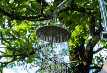 Cabeza de ducha exterior con agua fluyendo entre árboles en Lodgetent Samburu, Eco domaine Le Camp, Francia.