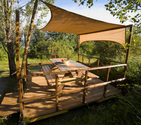 Udendørs terrasse med baldakin i træ ved Lodgetent Mont Kenya på Eco domaine Le Camp, Frankrig, om sommeren.