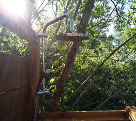 Udendørs bruser ved safaritelten Lodgetent Mont Kenya på Eco domaine Le Camp, omgivet af træer i solskin.