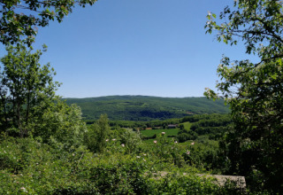 Uitzicht op groene heuvels en velden vanuit Lodgetent Mont Kenya bij Eco domaine Le Camp, Frankrijk.