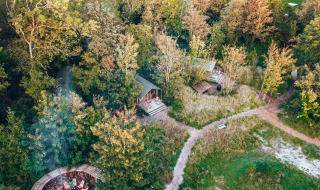 Vista aérea de cabañas pequeñas en el bosque cerca de Oostende, Bélgica, rodeadas de árboles y senderos.
