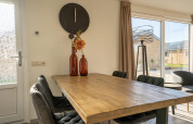 Dining area at Velthorst lodge, Zilverstrand Belgium, with wooden table and large glass sliding doors.