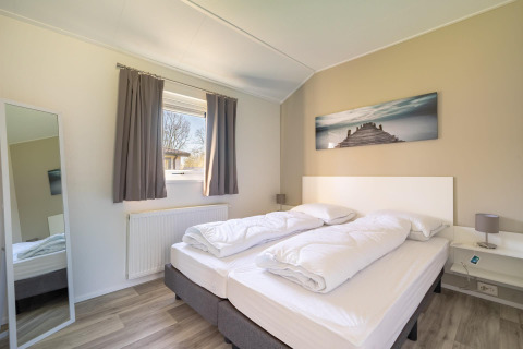 Modernes Schlafzimmer in der Velthorst-Lodge am Zilverstrand in Belgien mit Doppelbett und Wandbild.
