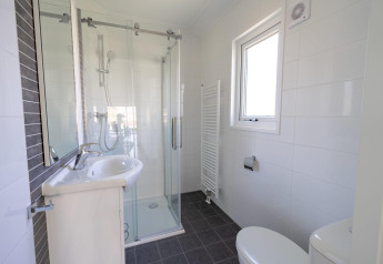Baño moderno en la cabaña Velthorst en Zilverstrand, Bélgica, con ducha, lavabo y ventana.
