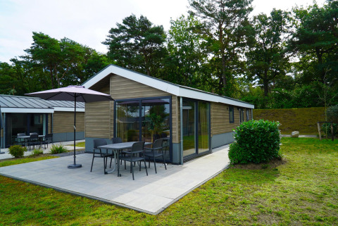 Moderne Velthorst-Lodge mit Terrasse und Gartenmöbeln im Zilverstrand, Belgien, umgeben von Natur.