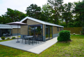 Moderne Velthorst-Lodge mit Terrasse und Gartenmöbeln im Zilverstrand, Belgien, umgeben von Natur.