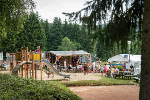 Kinderen spelen op een speelplaats bij lodge Sunshine in Petite Suisse, België, met gezelschappen rondom.