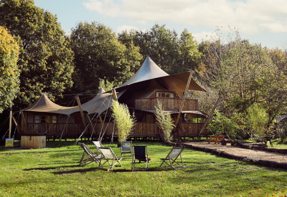 Tienda glamping Hacienda en Resort de Parel, Países Bajos, rodeada de árboles y sillas al aire libre.